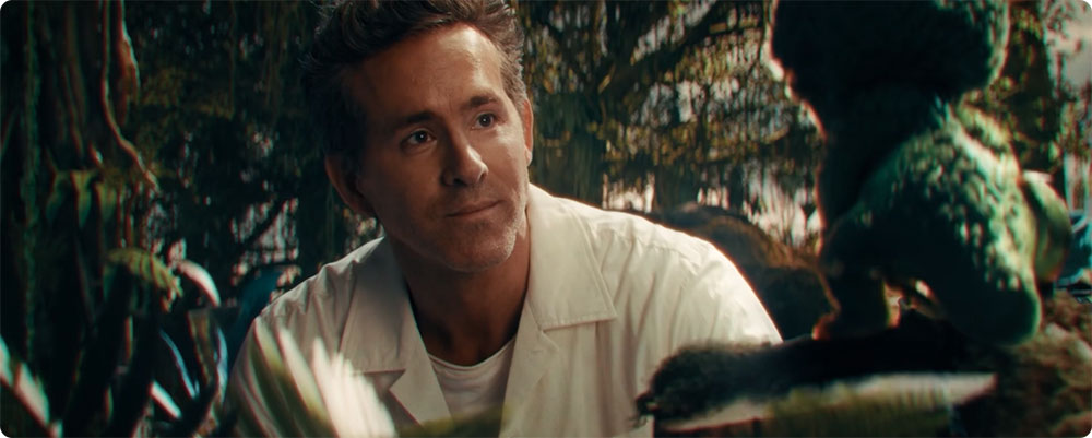 Close-up of Ryan Reynolds interacting with a small, animated character onscreen